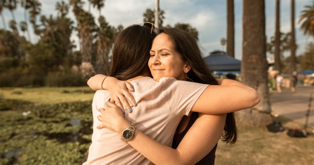 Two best friends hugging with joy and love in a park setting