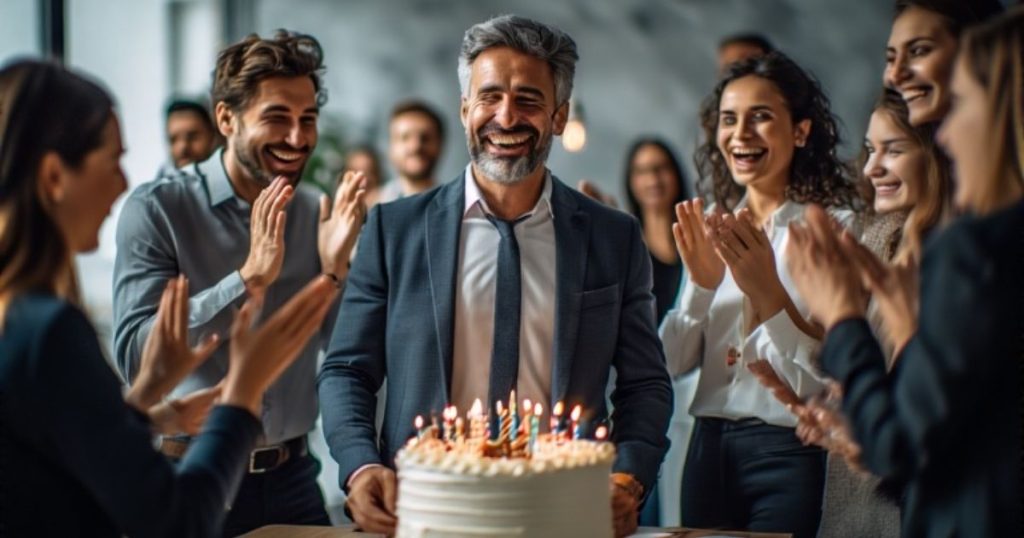 Office team celebrating boss’s birthday with a cake and claps